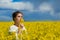 Brunette girl in rapeseed field  summer time, facing side way blue sky background