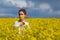 Brunette girl in rapeseed field  summer time, facing side way blue sky background.