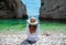 Brunette girl seen from behind sitting on the beautiful beach of Stiniva on the island of Vis in Croatia. Amazing scenery,