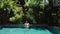 Brunette girl showing namaste hands greeting in outdoor swimming pool