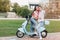 Brunette girl showing tongue while posing with boyfriend on scooter. Outdoor portrait of funny loving couple fooling