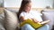 Brunette girl sitting on a sofa reading a book, turning pages.