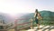 A brunette girl stands on an observation deck in the mountains and admires the beautiful view. A traveler with a backpack resting