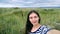 Brunette girl in the striped shirt taking a selfie on the beach. Sandy beach with dunes. Wind cloudy cool weather