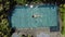 Brunette girl is swimming in outdoor pool on villa between tropical plants