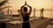 A brunette girl with tied hair in a black sports summer uniform holds her hands together above her head. Meditation on