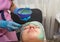 A brunette girl undergoes procedures in a spa salon, a master beautician in blue gloves applies a thick layer of a green mask,