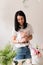 brunette girl in white t-shirt collects a bouquet of flowers from roses florist at work