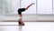 Brunette girl in a white top and black shorts and bicycles doing a headstand