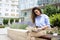 Brunette haired woman sitting on a bench in the city and using a laptop for work