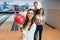 Brunette is happy to be there. Young cheerful friends have fun in bowling club at their weekends