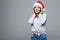 Brunette in hat of Santa Claus on blank gray