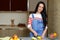 Brunette housewife in blue overalls cuts an apple in the kitchen