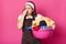 Brunette houseworker holding her nose with one hand, having full pink basin of bad smelling items of clothes, trying to bear smell