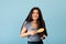 Brunette Indian teen girl brushing her beautiful long hair with natural wooden brush on blue studio background