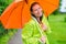 Brunette laughing under an orange umbrella