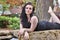 Brunette lays on stone over water, looking at the camera