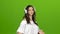 Brunette listens through the headphones with energetic music and builds grimaces. Green screen