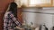 Brunette with long hair in a plaid shirt clears congestion in the sink with the plunger.