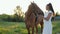 Brunette with long hair in ponytail walks with horse