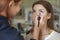 Brunette make up artist woman applying make up for a caucasian b