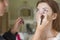 Brunette make up artist woman applying make up for a caucasian b