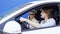 Brunette man and blonde woman are travelling by white car with blue background. Young driver is shouting loudly and