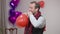 Brunette man blowing heart shape balloon on Valentine's day indoors and walking away. Portrait of loving romantic