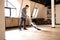 Brunette man vacuuming wooden floor in loft iving room