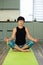 Brunette middle aged woman doing yoga meditation on exercise mat at home, mental health. Peaceful woman meditate, mental