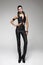 Brunette model in detailed gothic black stylish jumpsuit and heeled black boots. White background, studio. Future fashion design