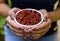 Brunette model hand holding white pot with goji berry