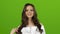 Brunette shows a finger up winks and sends a kiss. Green screen. Close up