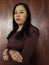 brunette skin mexican woman with brown sweater posing with wooden background