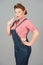 Brunette styled girl in denim on gray background. Portrait of attractive repair woman in pin-up style