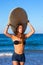 Brunette surfer teen girl holding surfboard in a beach