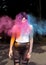 Brunette tattooed woman posing with blowing Holi powder at the p