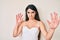 Brunette teenager girl posing elegant afraid and terrified with fear expression stop gesture with hands, shouting in shock