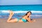 Brunette tourist lying in beach sand tanning happy