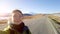 A brunette traveler girl takes a selfie on the background of an asphalt road in the direction of mount Elbrus. Hitchhiking.