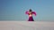 Brunette with a veil in her hands dances a belly dance in the desert. Slow motion