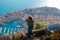 Brunette wearing blue jeans and blue top seen from behind standing on the mountain above the city of Dubrovnik, amazing town seen