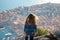 Brunette wearing blue jeans and blue top seen from behind standing on the mountain above the city of Dubrovnik, amazing town seen