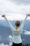 Brunette woman with back facing the camera, raises arms while enjoying the mountain view at Olympic National Park in Washington