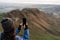 Brunette woman backwards taking a photo from the peak of a mountain during winter