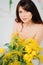 a brunette woman with bare shoulders with a bouquet of yellow tulips and mimosa