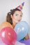 Brunette Woman in a Birthday Cap Holding Balloons and Smile