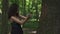 brunette woman in black lingerie playing with axe and cuts the tree. Green forest background