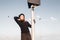 Brunette woman in black turtleneck standing at pole with loudspeaker and looking into the distance