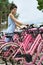 Brunette woman in blue dress on outdoor parking of pink bikes